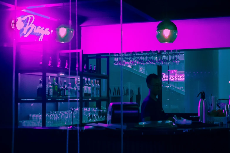 person sitting in bar with neon purple light