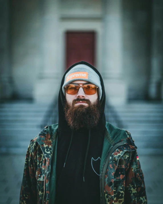 a person with a beard and sunglasses in front of a building