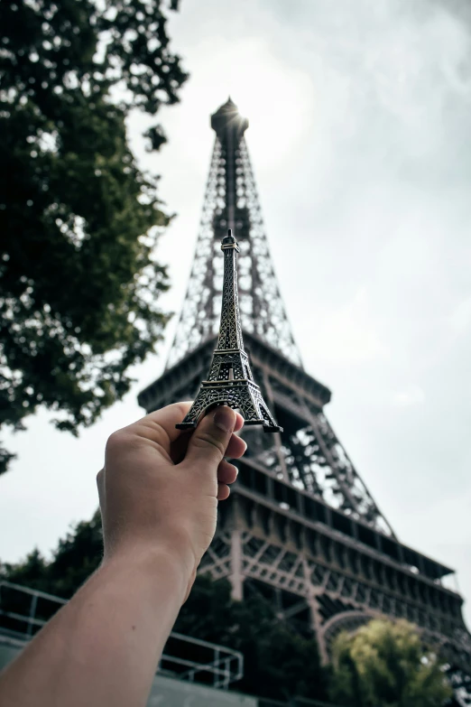 a hand holding a tiny tiny model of the eiffel tower