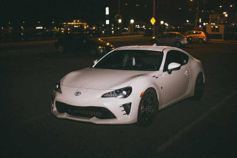 a white sports car parked in a parking lot at night