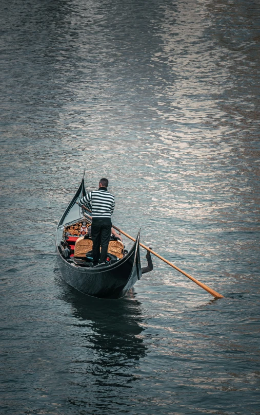 a man wearing an striped shirt is paddling a small boat