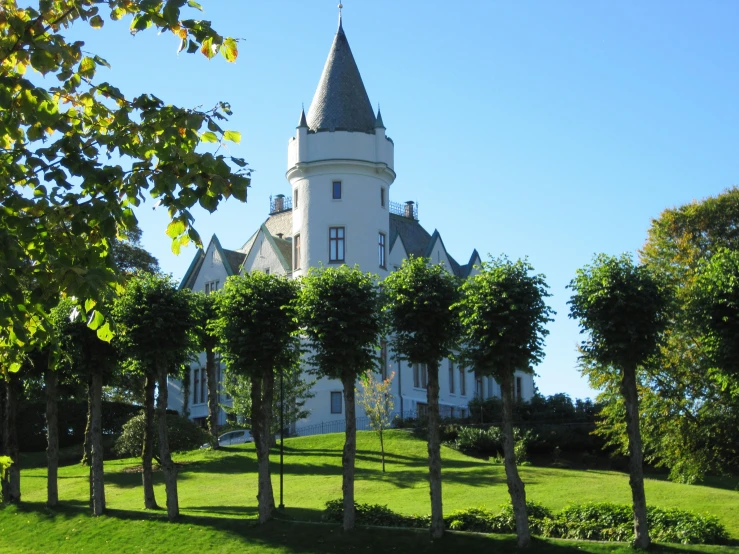 a tall white building sitting on top of a lush green field