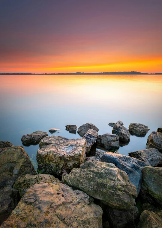 rocks by the water at sunset or sunrise over them