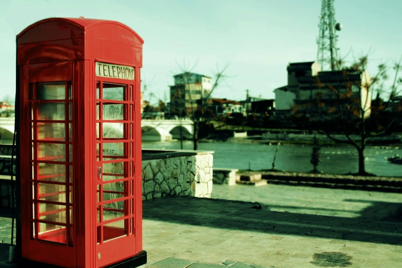 a red phone box on a sidewalk in front of some buildings