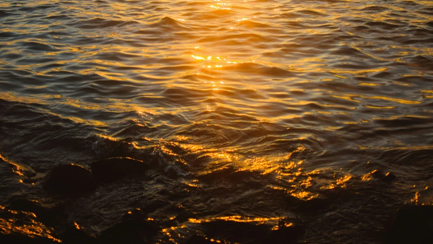 sun setting over the water and waves on a beach