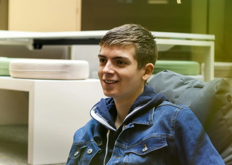 a man sitting on a chair with a  pad and table in the background