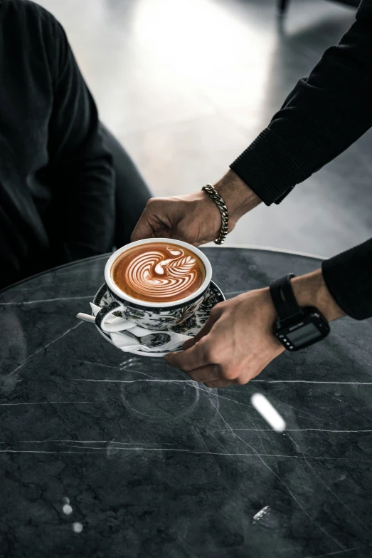 people holding a cup of chocolate drink while sitting at a table