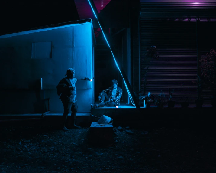 two people standing in the dark next to some buildings