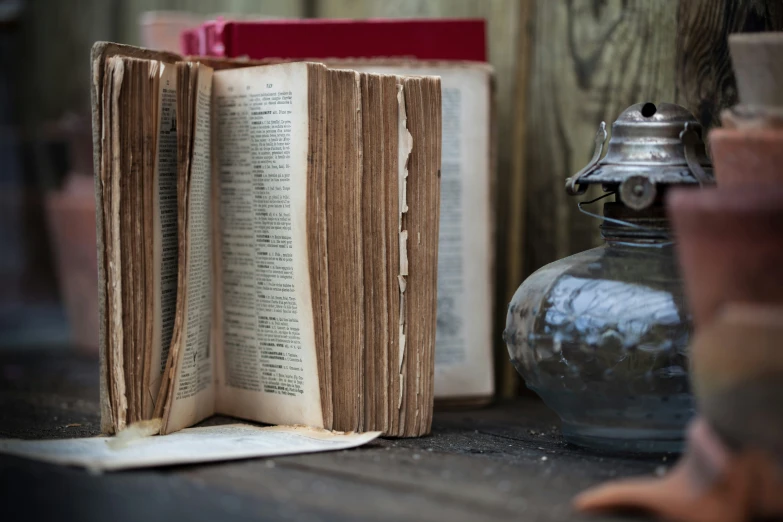 the open book is sitting near a metal vase