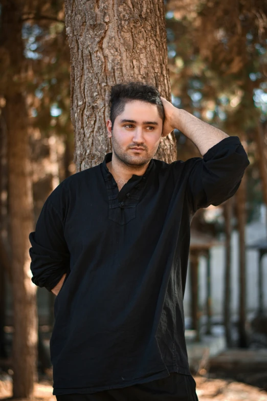 man standing against a tree wearing a black shirt