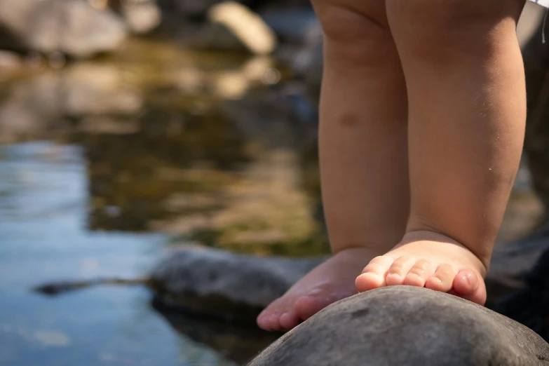 someone with barefoot feet is standing on rocks near water