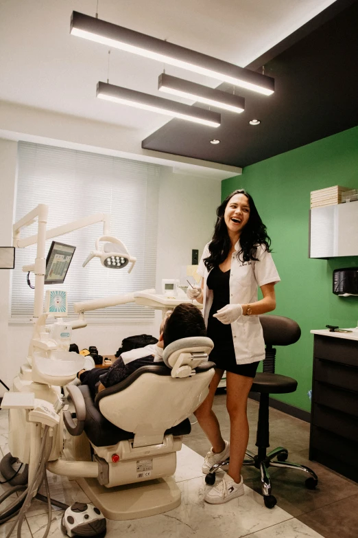 woman with black dress standing next to dental equipment