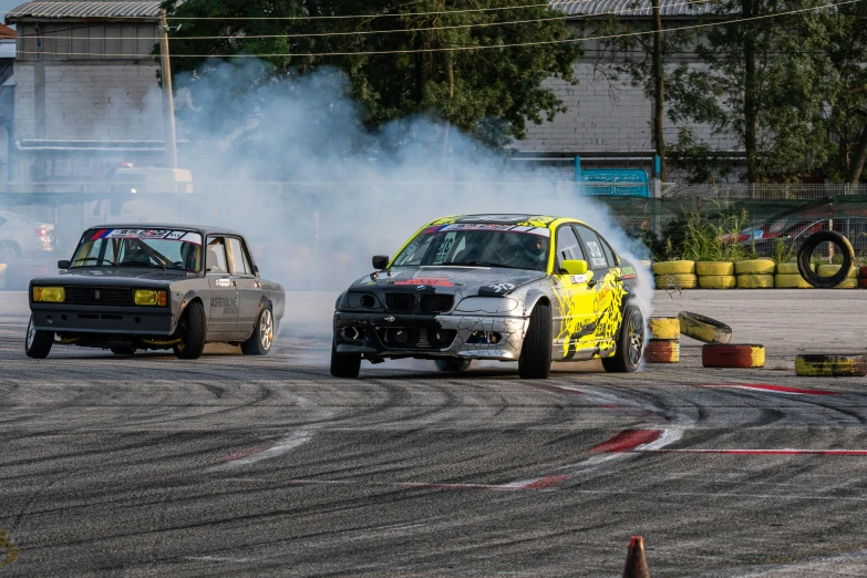 the two cars are driving on the track as smoke comes out from the exhaust