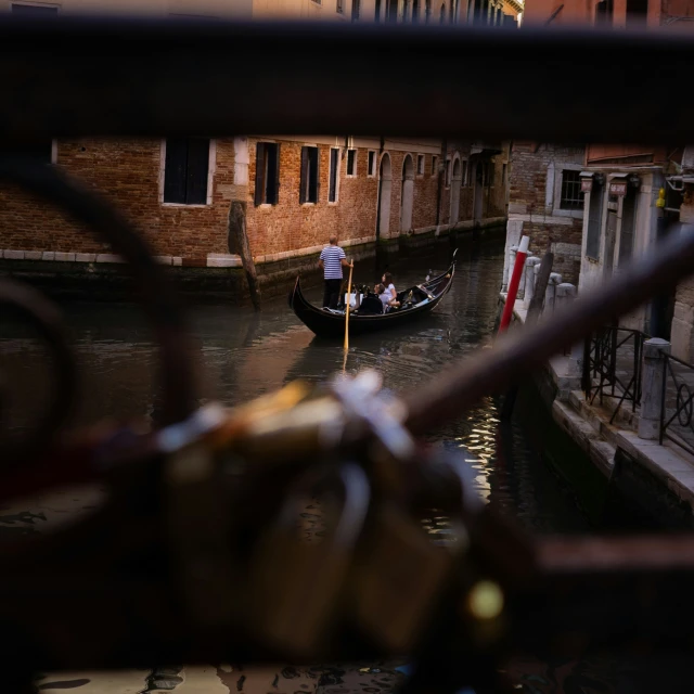 a couple of people riding on the back of a boat down a canal