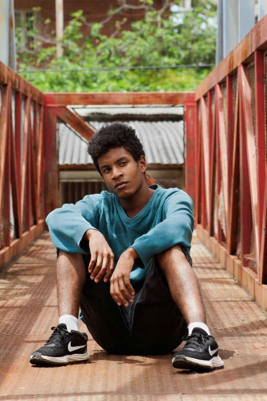 a man is sitting on a bridge with his arms crossed