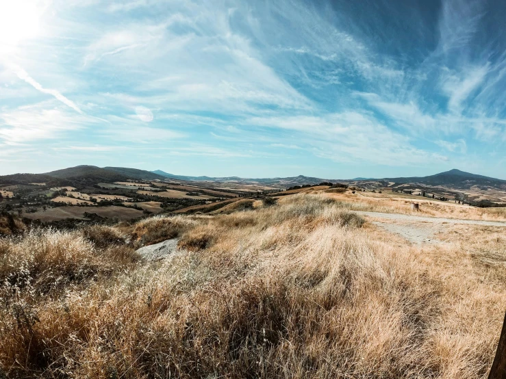 a field with dirt road and a brown grass hill