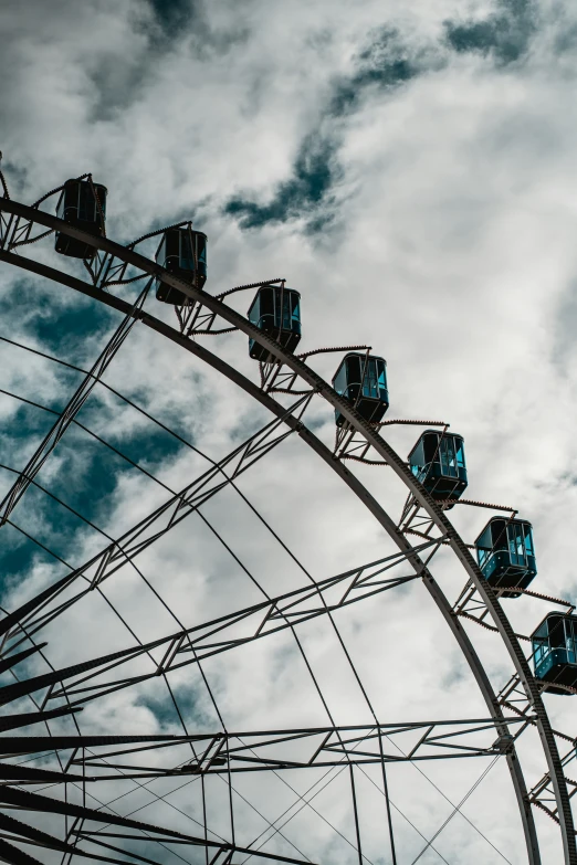 the large ferris wheel is almost invisible against the cloudy sky