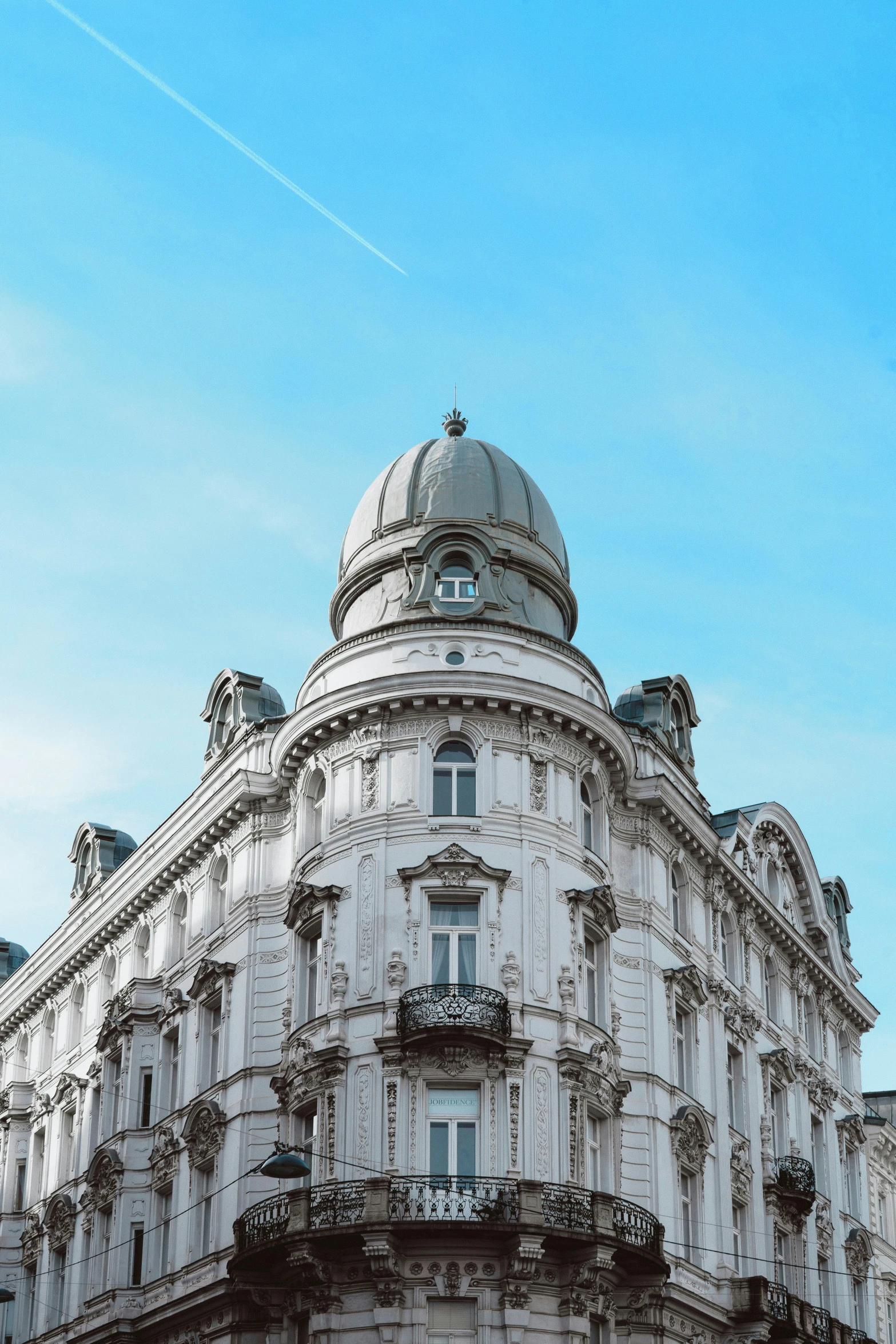 the building is white with blue sky and clouds