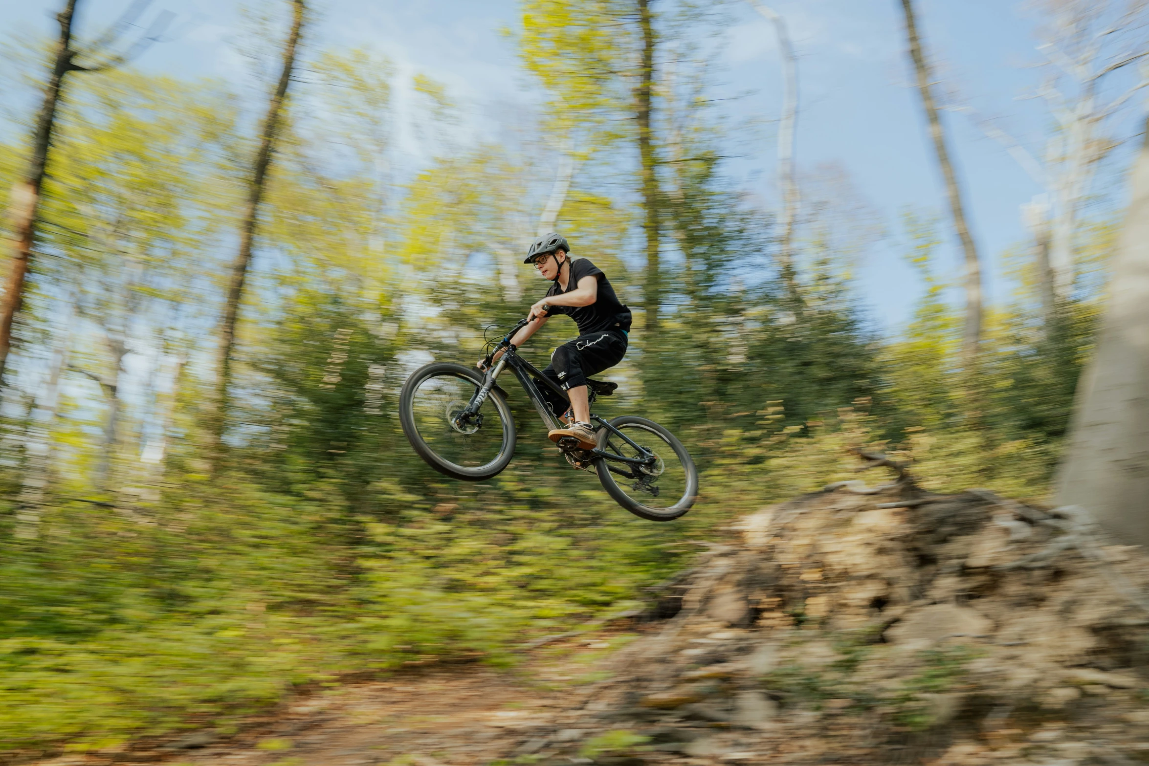 man in full bike gear flying through the air on dirt and rock path