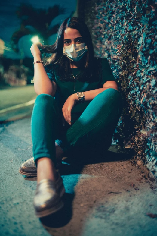 a person sitting on the ground in blue pants and a mask