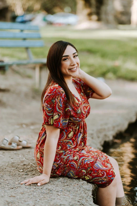 a woman wearing a red dress is sitting down by the water