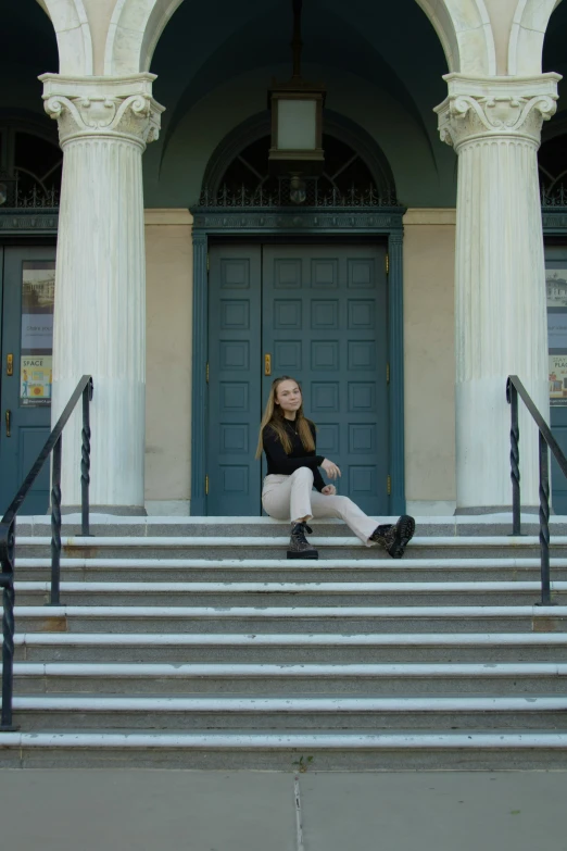 a woman sits on the steps of a building