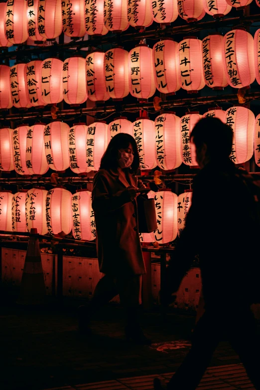 a couple walking past a wall of lanterns