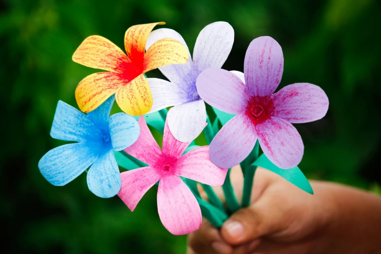 a person is holding three fake paper flowers