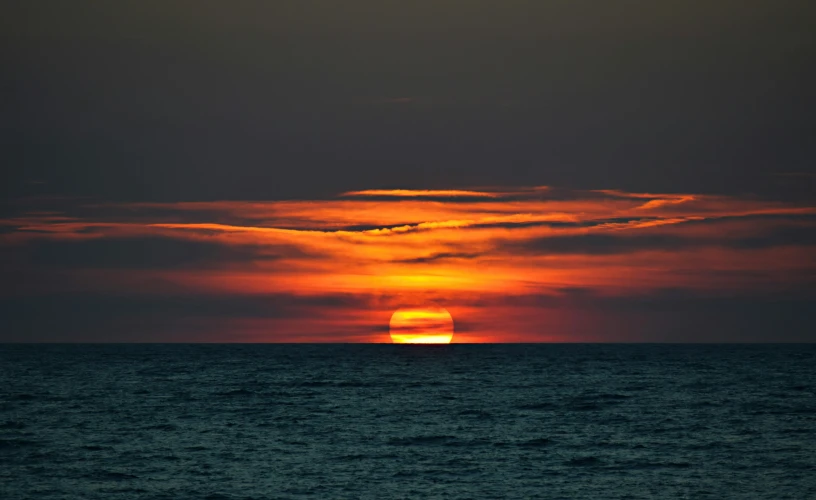 a sunset is seen in the background behind the water