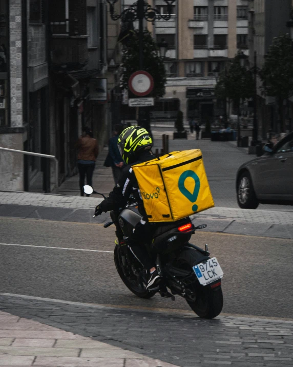 a motorcyclist in helmet and yellow protective gear rides down the street