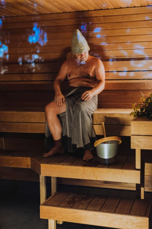 an older man in a shower sits on a bench and washes his hair