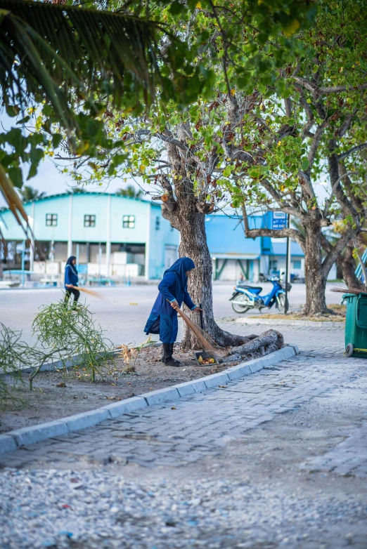 the two people are near a tree and garbage cans