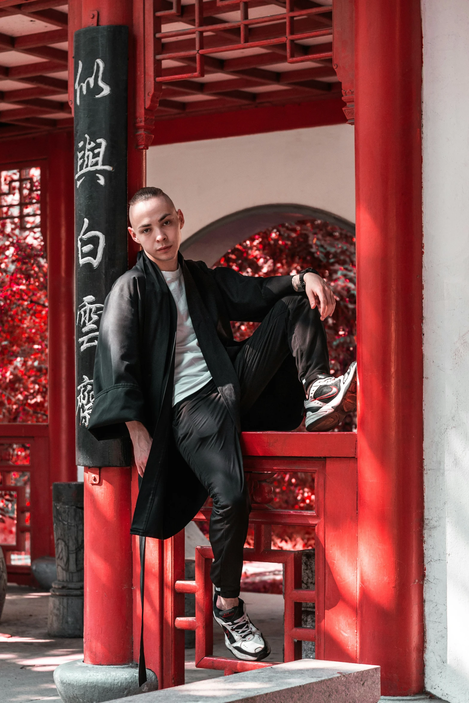 a young man sitting on top of a red wooden bench in front of a building