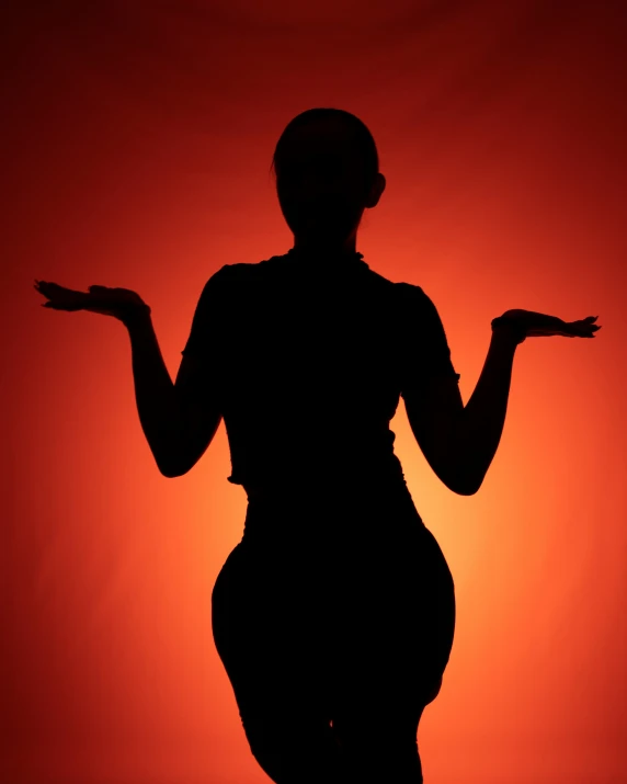 silhouette image of a woman holding her arms outstretched in front of an orange and red sky