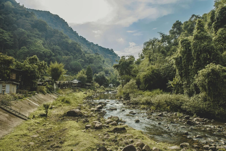 a river runs through the green mountains in the middle of the day