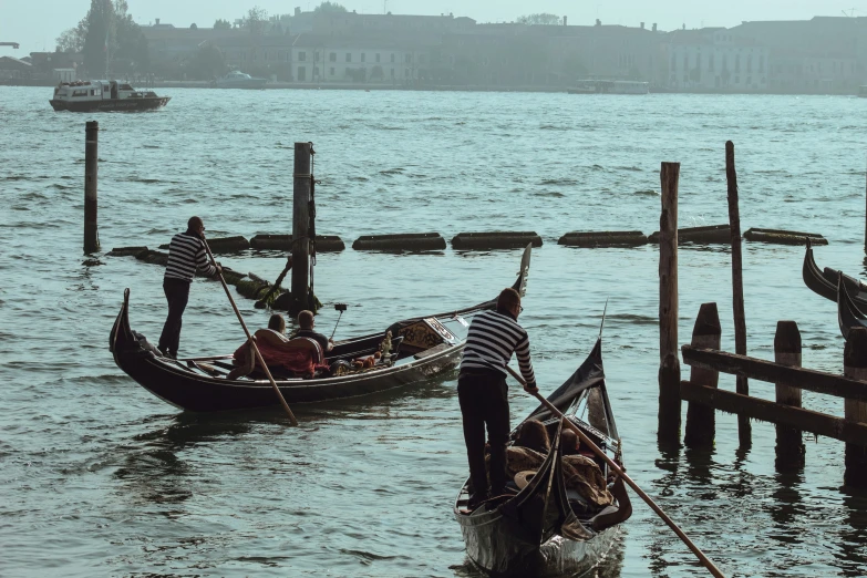 several gondolas tied up to posts in a body of water