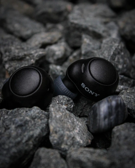 a group of two sony headphones laying on the rocks