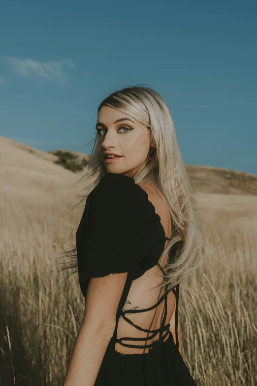 blonde hair girl in black top standing in field