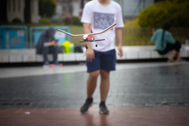 a man standing near some buildings with a small bike