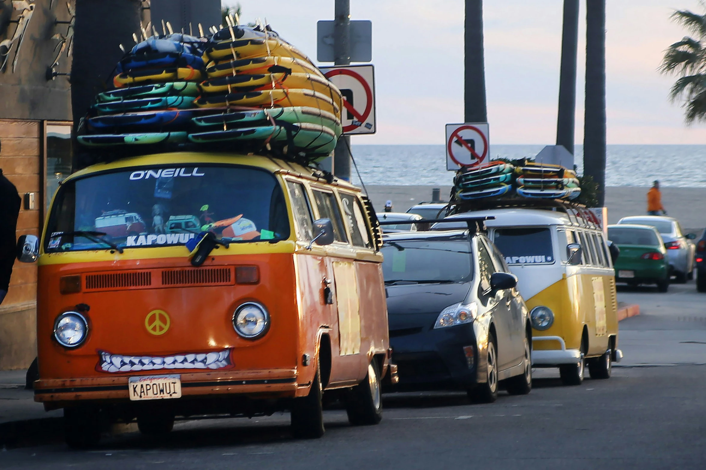 some old vw buses are driving down the road with surfboards stacked on top