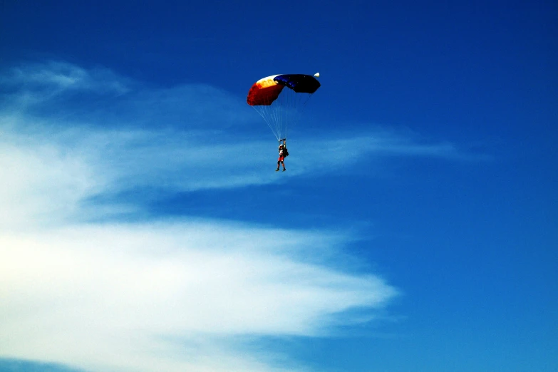 a parasailer flying against a blue cloudy sky