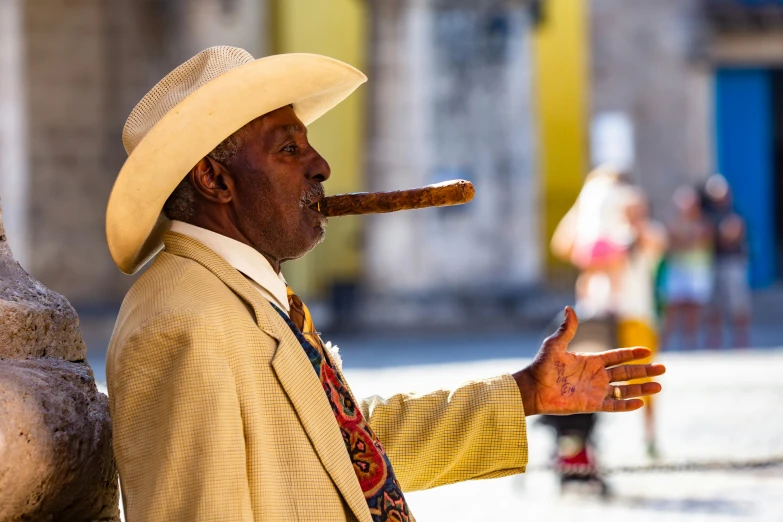 a man smoking a cigar while standing next to some statues