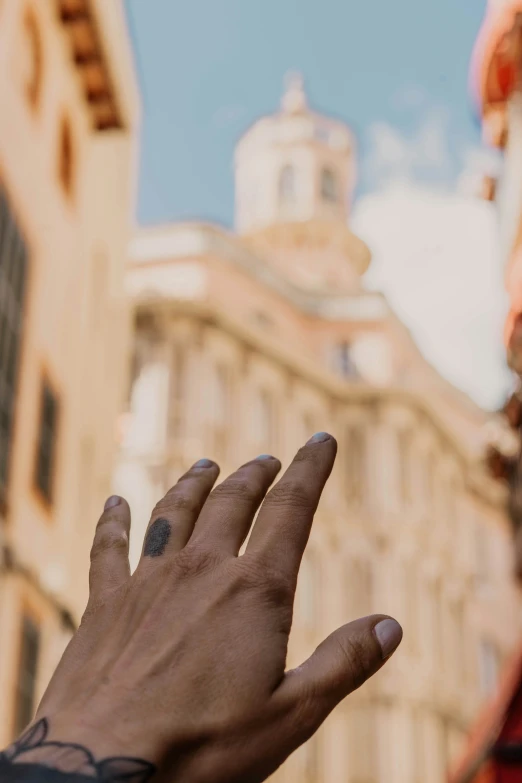 a man with a tattoo on his ring reaching out to the sky