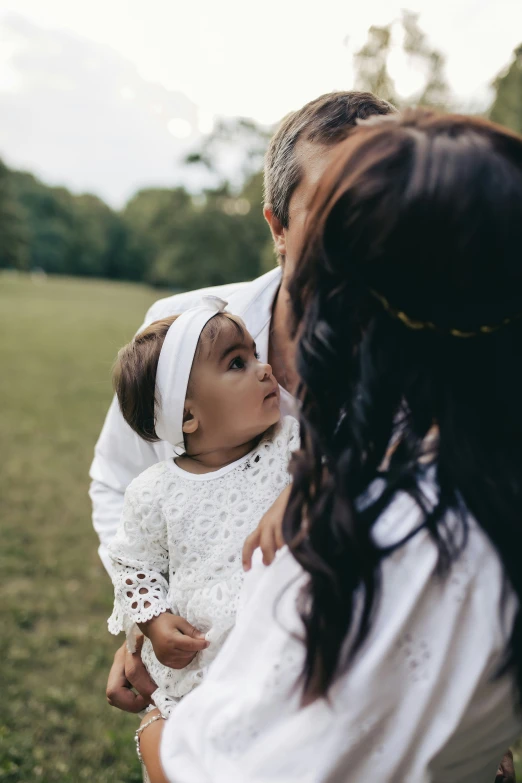 a woman holding a small child who is wearing a dress