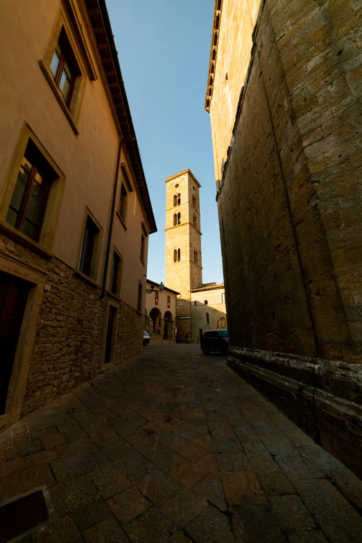 an alleyway with tall buildings and a tower