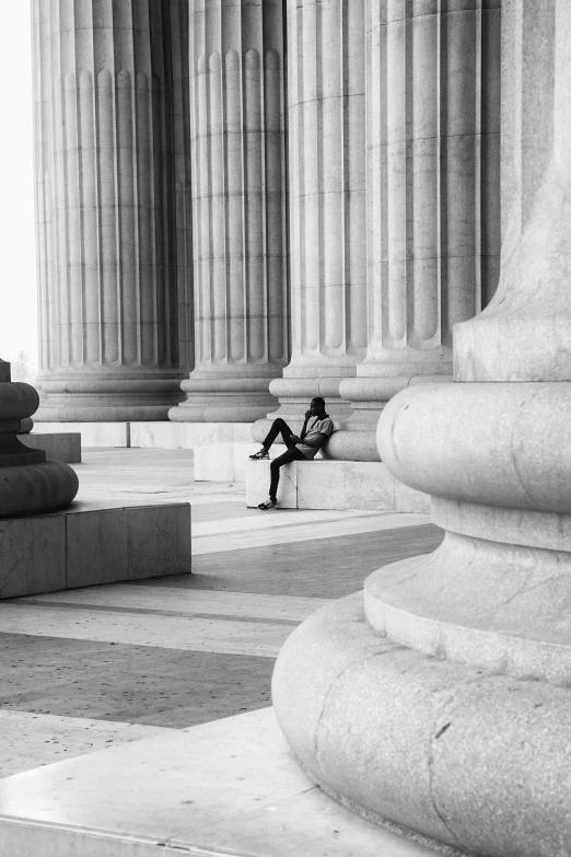 a person sitting outside a large building with columns