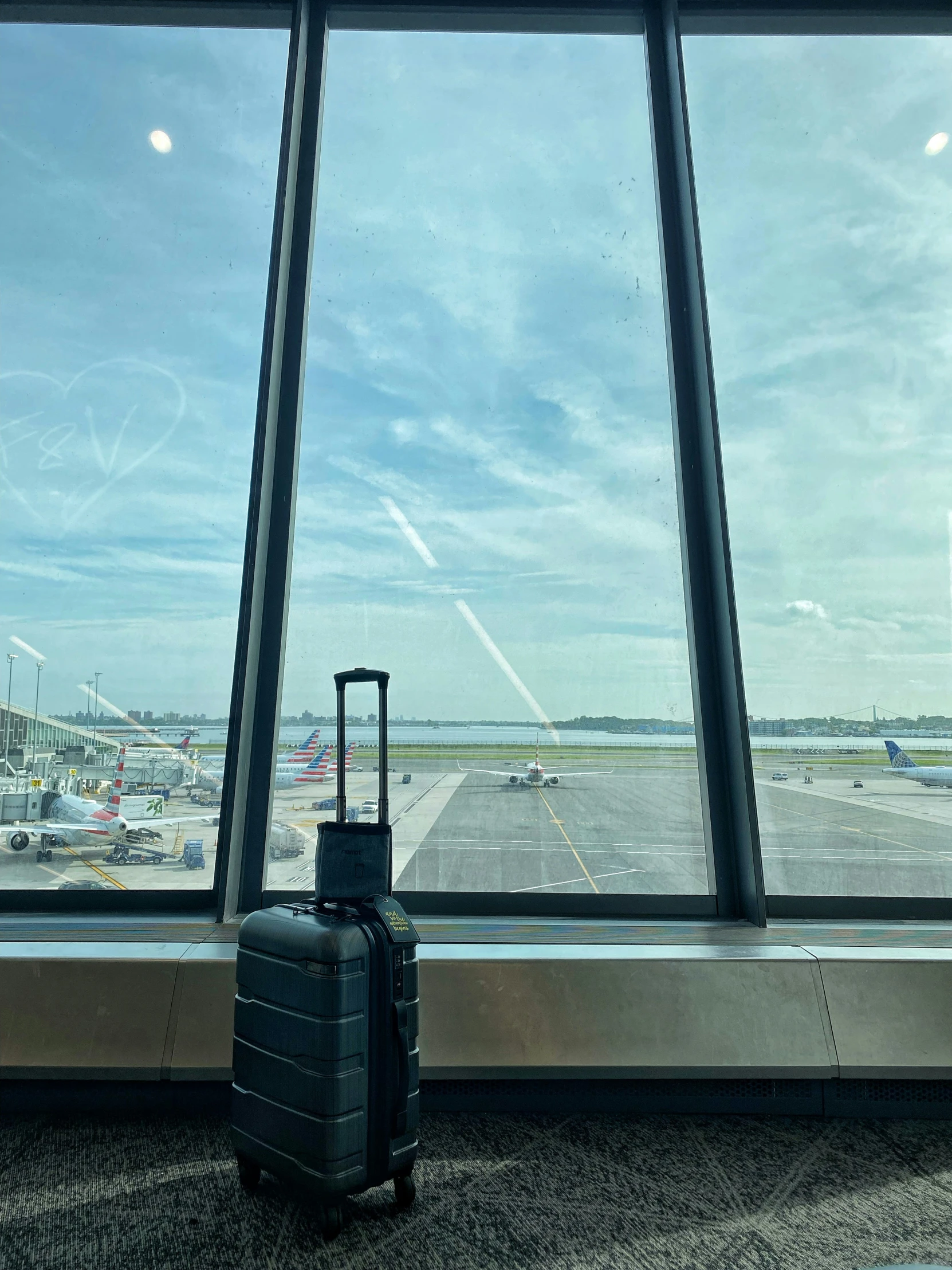 a large window overlooks an airport with a rolling luggage