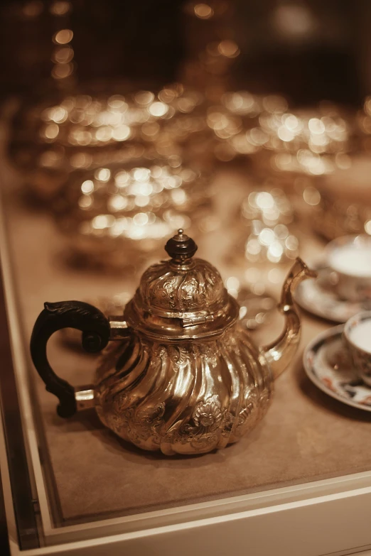 a gold teapot is set up with cups