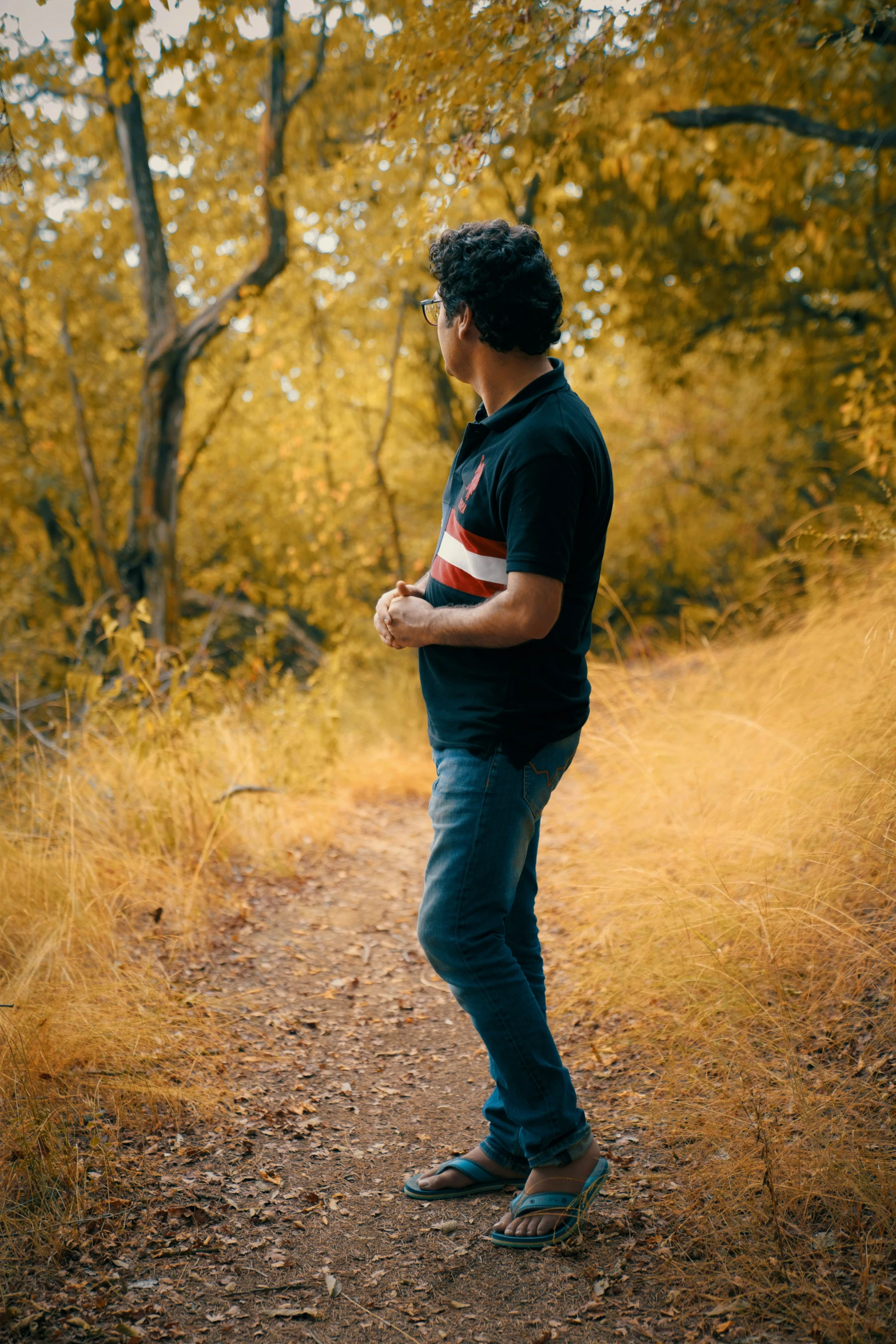 a man standing in the middle of a leaf filled park