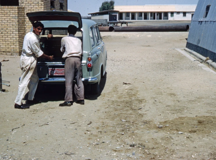 two men in a parking lot unloading and unpacking a car